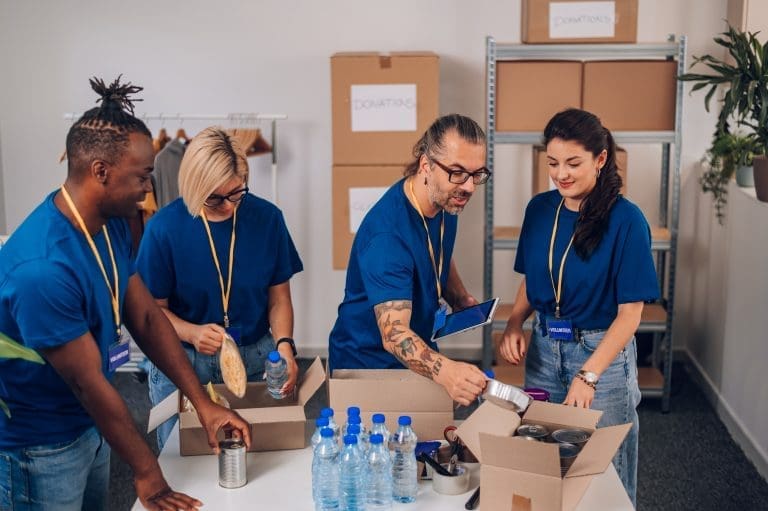 Diverse volunteers working in a charity donation center and packing clothes and food