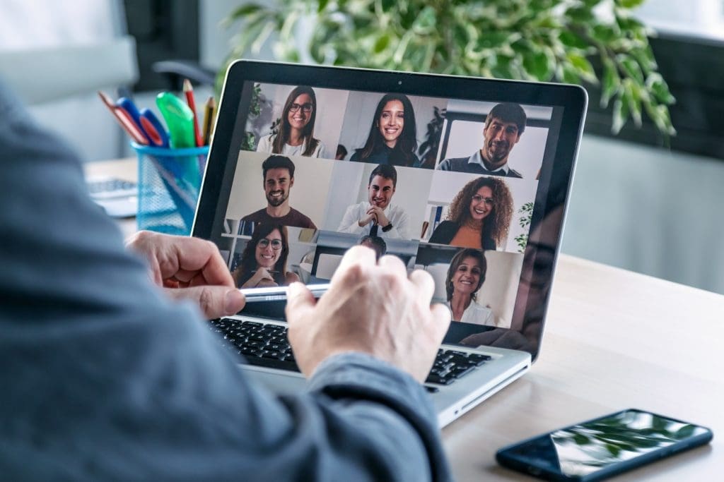 Back view of male employee speaking on video call with diverse colleagues on online briefing with laptop at home.